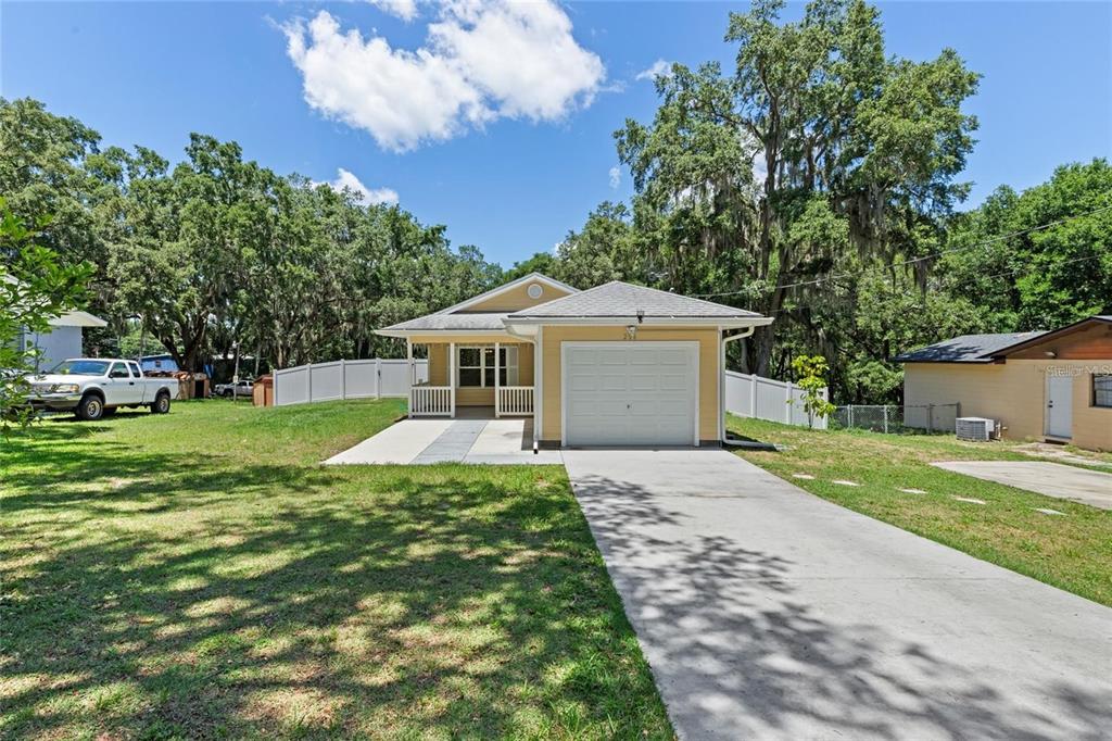A yellow single-story house with a front-facing garage and a concrete driveway — 206 E CATAWBA, FRUITLAND PARK, FL