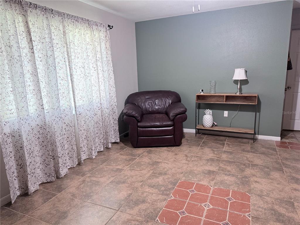 A room with tile flooring, a dark leather armchair, and a console table against a wall — 1420 BELLEVIEW ROAD, COCOA, FL