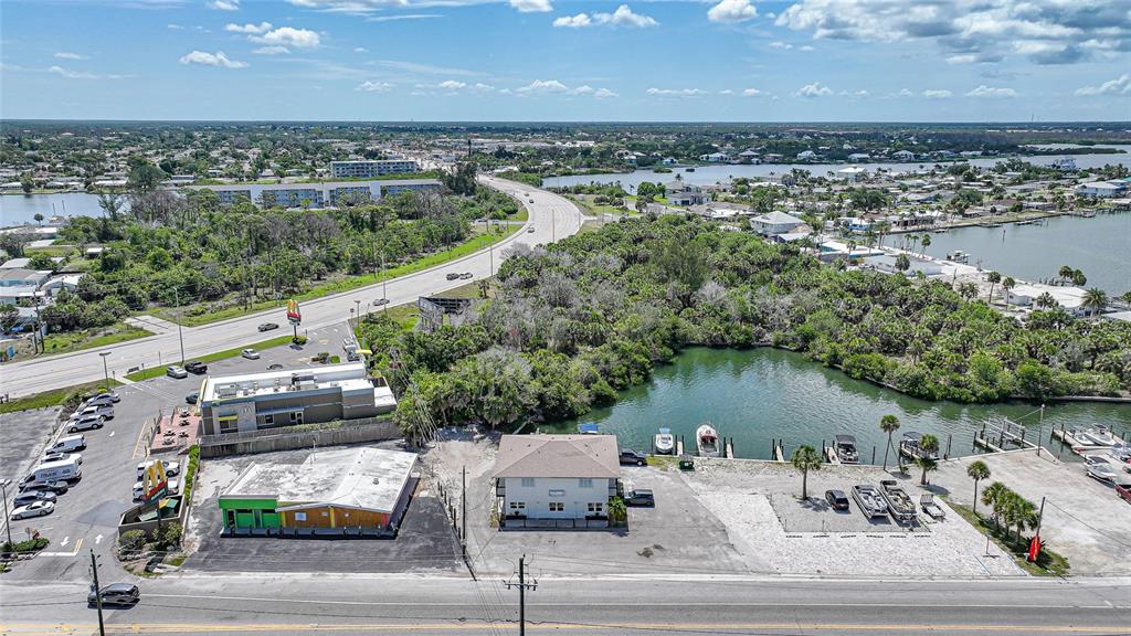 An aerial view shows a commercial property with a parking lot, buildings, and boat slips — 1261 BEACH ROAD, ENGLEWOOD, FL