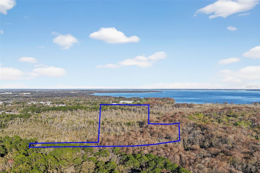 An aerial view shows a plot of land outlined in blue near a large lake — 1721 COUNTY ROAD 25A, LEESBURG, FL