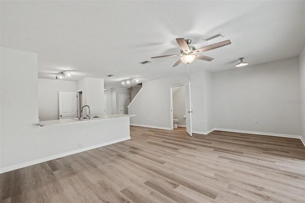 An open-concept living area features light wood-look flooring, a kitchen island, and a ceiling fan — 9974 HOUND CHASE DRIVE, GIBSONTON, FL
