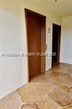 A hallway features two wooden doors and light-colored hexagonal floor tiles — 198 E Mansfield  E # 198, Boca Raton FL 33434, BOCA RATON, FL