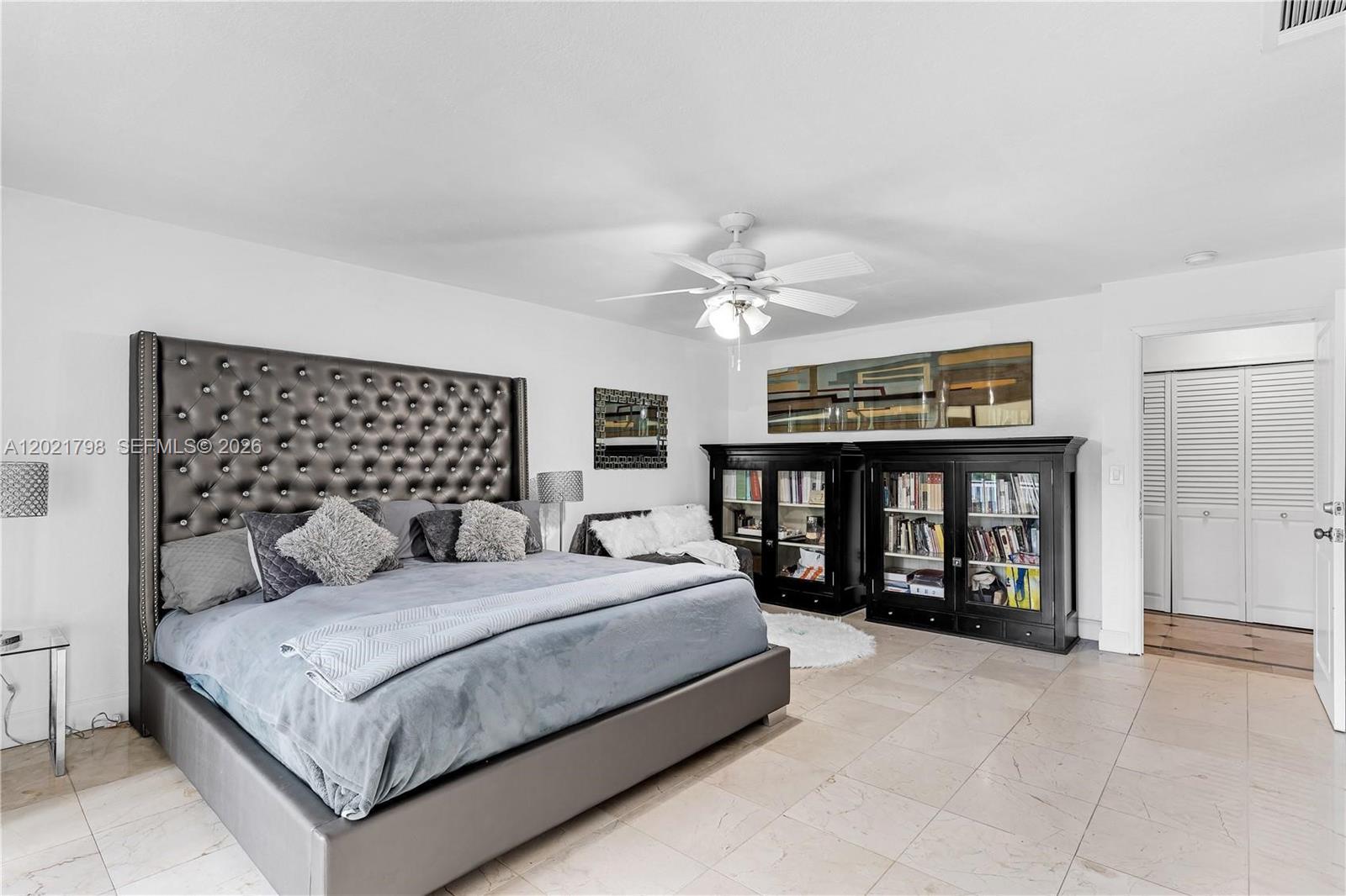 A bedroom features a tufted headboard, a ceiling fan, and black bookcases on tile flooring — 8909 SW 108th Cir Ct, Miami FL 33176, MIAMI, FL