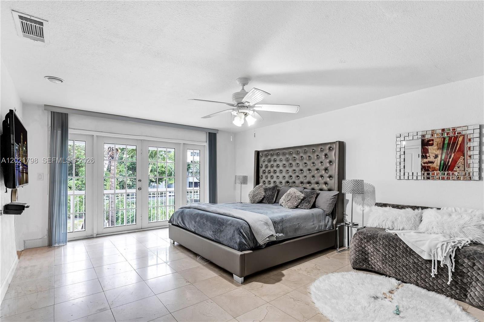 A bedroom features a tufted headboard, tiled floors, a ceiling fan, and glass balcony doors — 8909 SW 108th Cir Ct, Miami FL 33176, MIAMI, FL