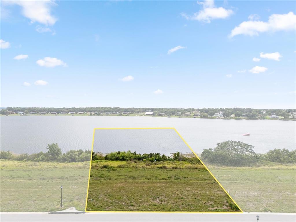 An aerial view shows a vacant, rectangular waterfront lot outlined in yellow near a lake — 4343 JULIANA LAKE DRIVE, AUBURNDALE, FL