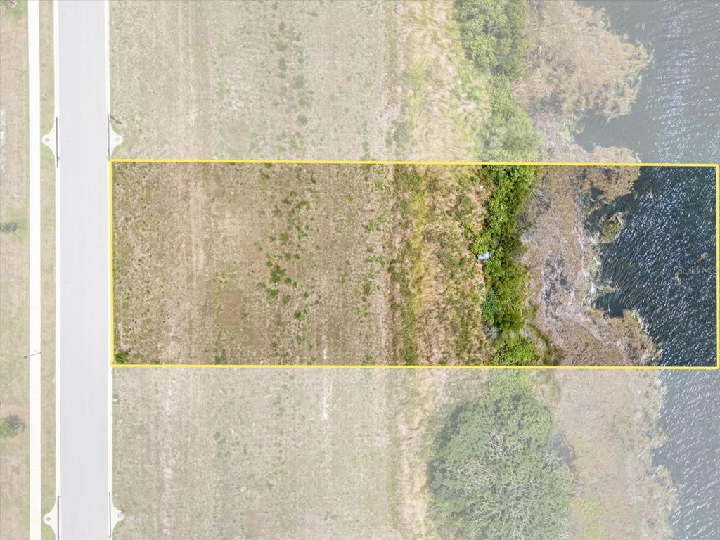 This aerial view shows a rectangular vacant lot bordering a road and a body of water — 4343 JULIANA LAKE DRIVE, AUBURNDALE, FL