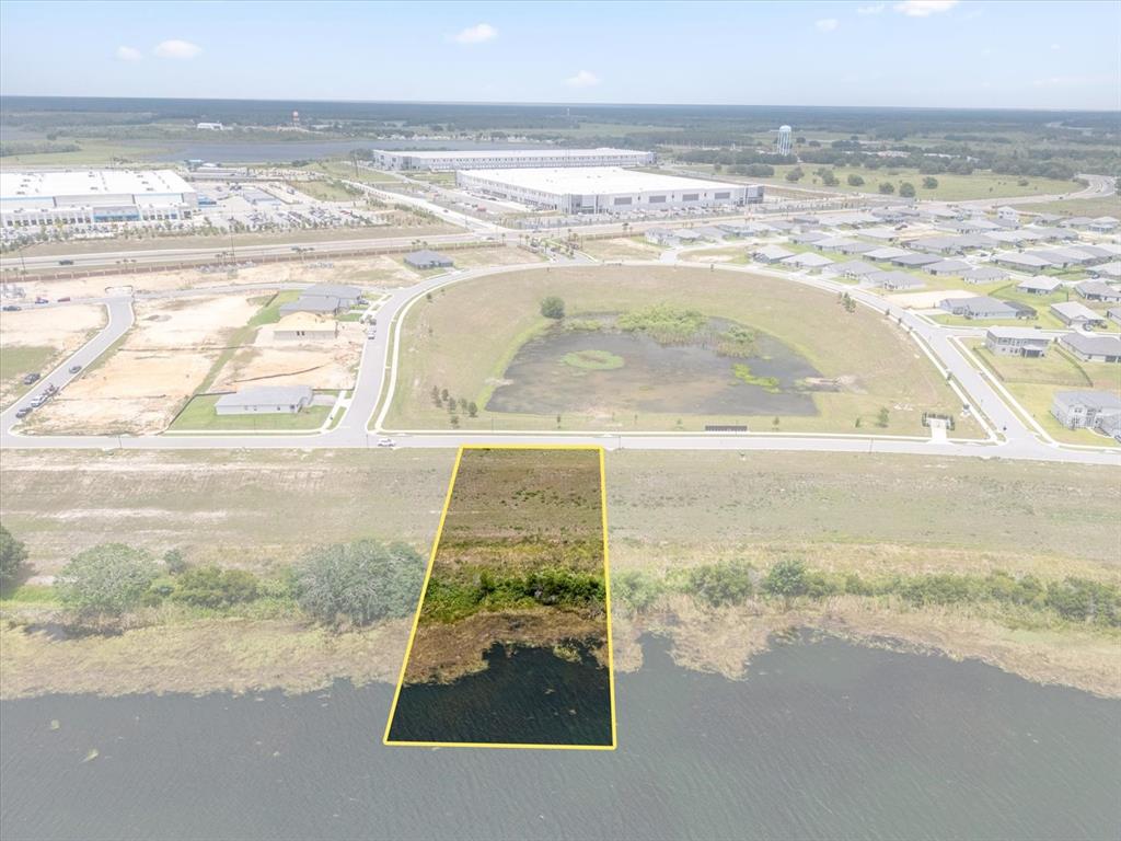 An aerial view shows a rectangular waterfront lot highlighted in yellow next to a residential neighborhood — 4343 JULIANA LAKE DRIVE, AUBURNDALE, FL