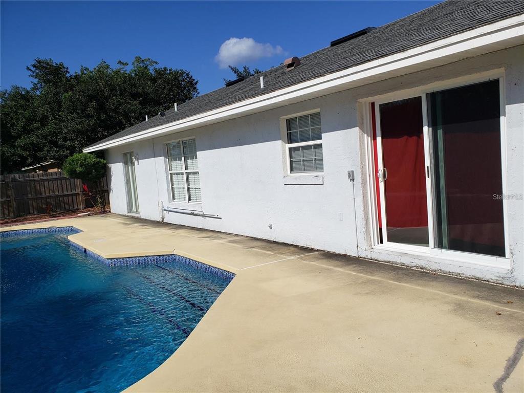 A white house exterior features a swimming pool and sliding glass doors on the patio — 3792 DUNWICH AVENUE, ORLANDO, FL