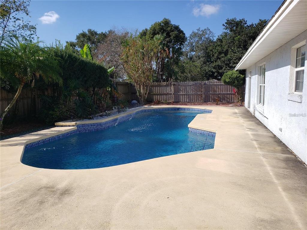 A backyard features an in-ground swimming pool with a concrete deck and a wooden fence — 3792 DUNWICH AVENUE, ORLANDO, FL
