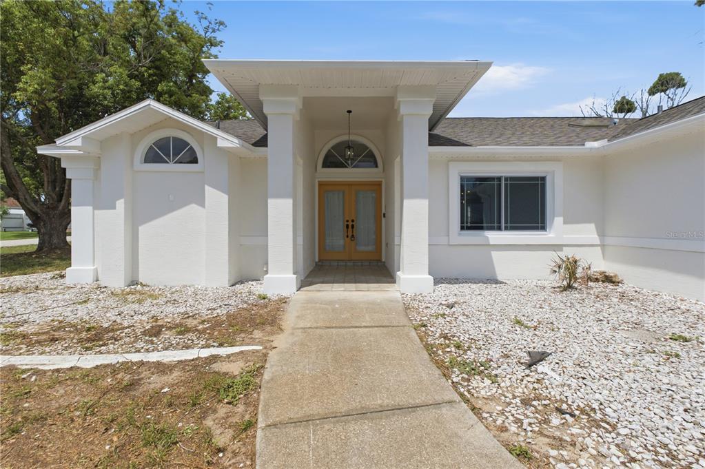 The exterior of a white house features a covered entryway with columns and double doors — 5098 WINTERVILLE ROAD, SPRING HILL, FL