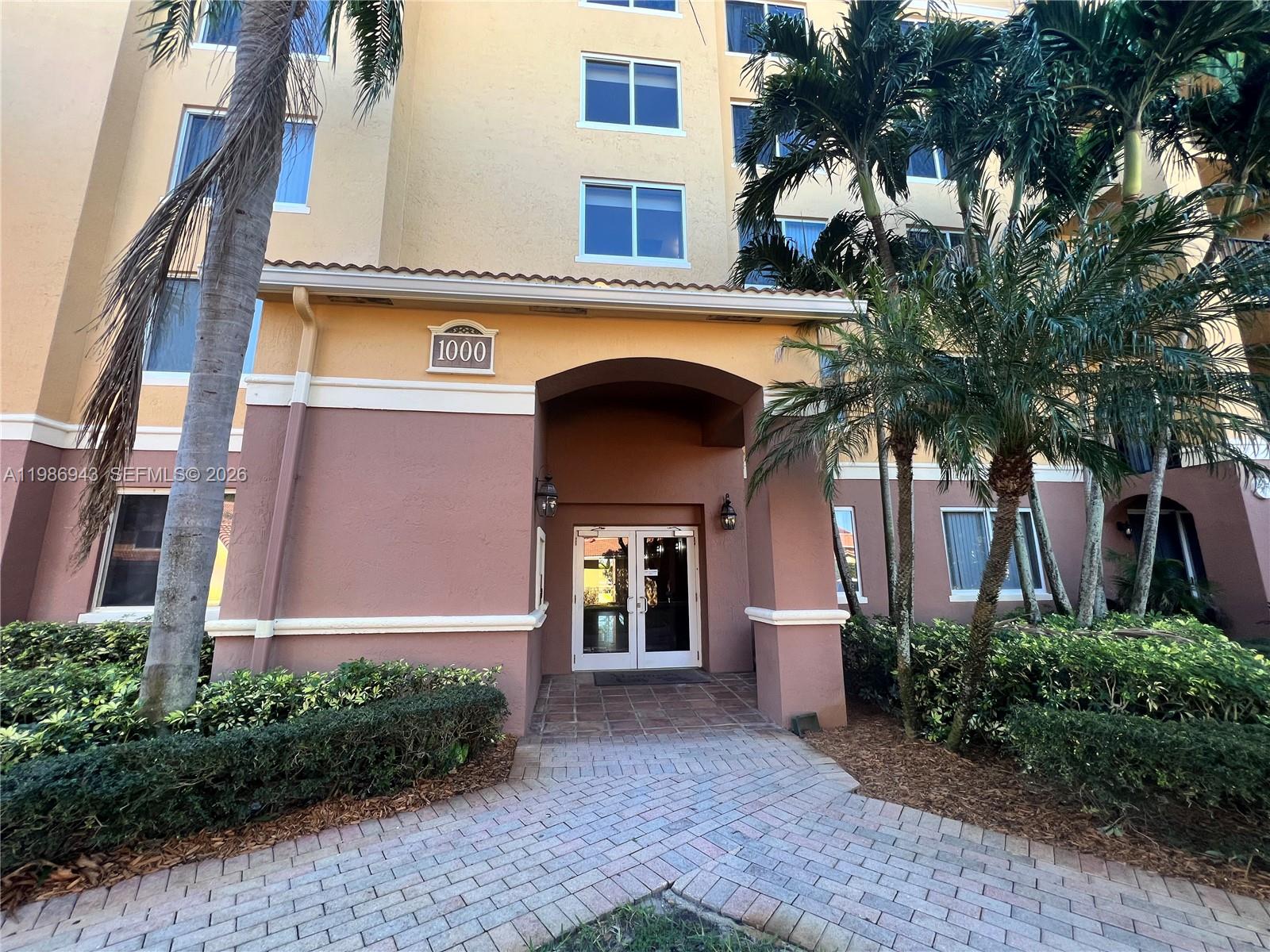 A paved walkway leads to the entrance of a multi-story building with palm trees — 1000 Scotia Dr # 101, Hypoluxo FL 33462, HYPOLUXO, FL