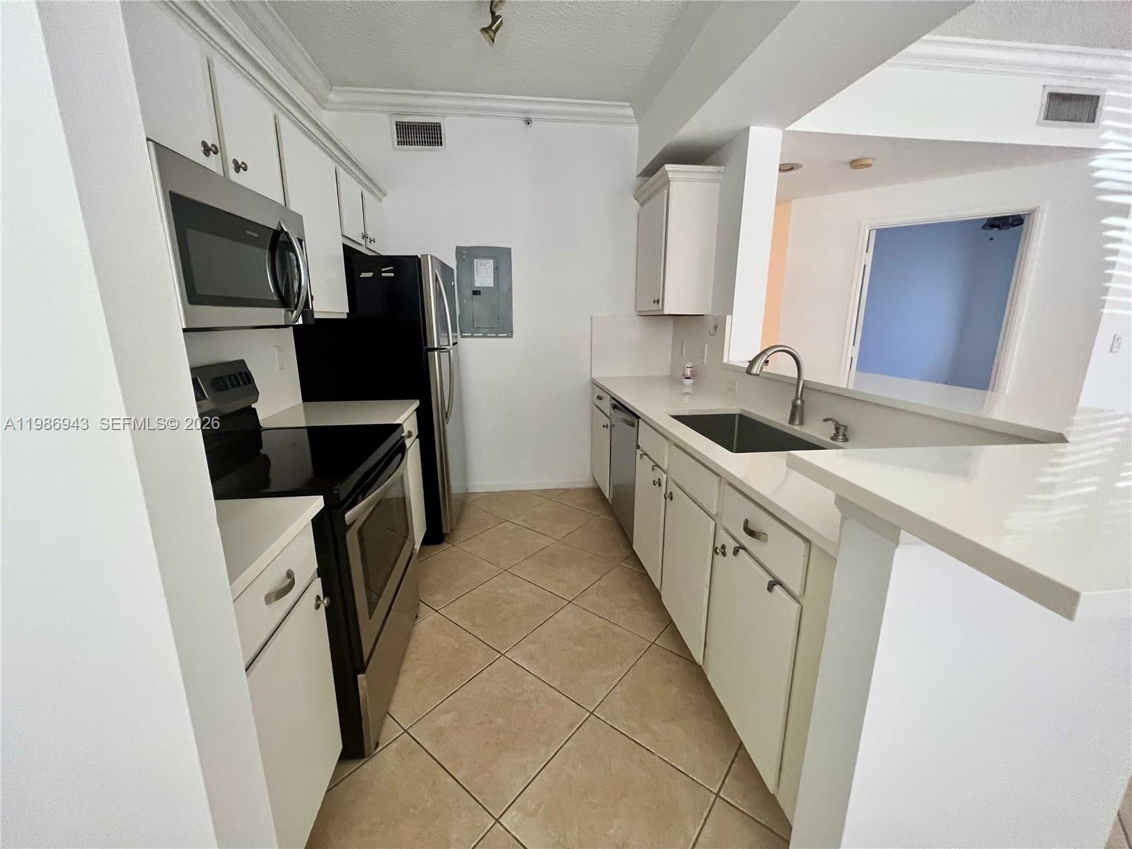 A kitchen features white cabinets, stainless steel appliances, a sink, and beige tile flooring — 1000 Scotia Dr # 101, Hypoluxo FL 33462, HYPOLUXO, FL