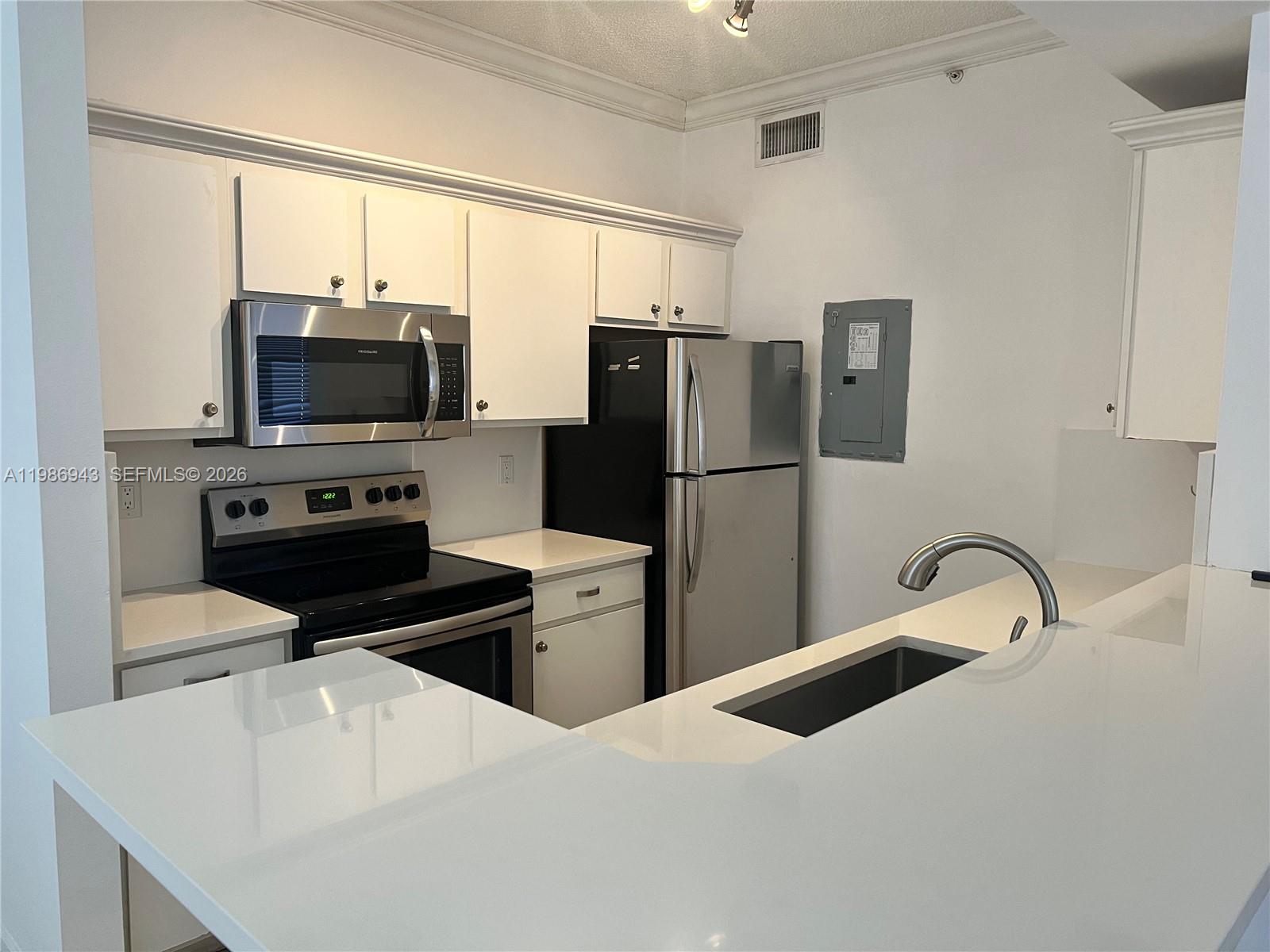 A kitchen features white cabinets, stainless steel appliances, and a white countertop peninsula — 1000 Scotia Dr # 101, Hypoluxo FL 33462, HYPOLUXO, FL