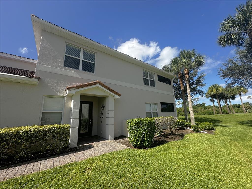 A two-story stucco house with a covered entryway, paved walkway, and surrounding landscaping — 14073 BLACK BEAUTY DRIVE UNIT 1012, PUNTA GORDA, FL