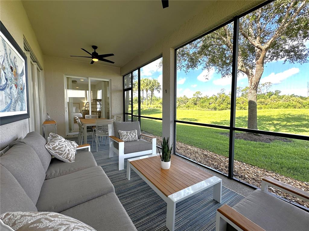 A screened-in patio features gray furniture, a wooden coffee table, and views of a grassy yard — 14073 BLACK BEAUTY DRIVE UNIT 1012, PUNTA GORDA, FL