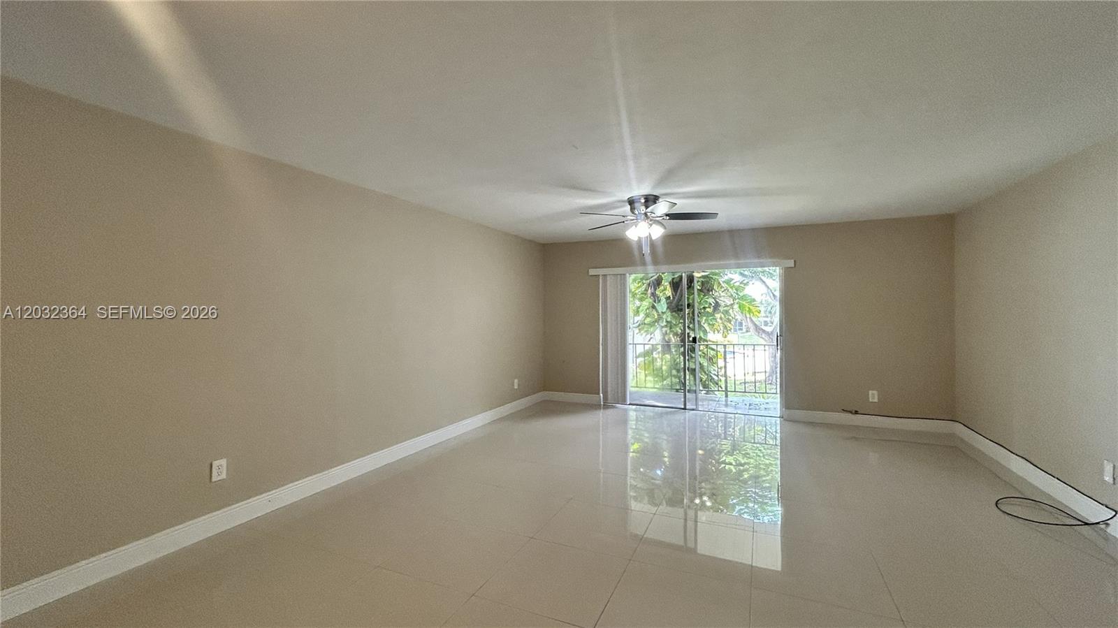 An empty room features beige walls, light-colored tile flooring, a ceiling fan, and sliding glass doors — 10377 N Kendall Dr # K8, Miami FL 33176, MIAMI, FL
