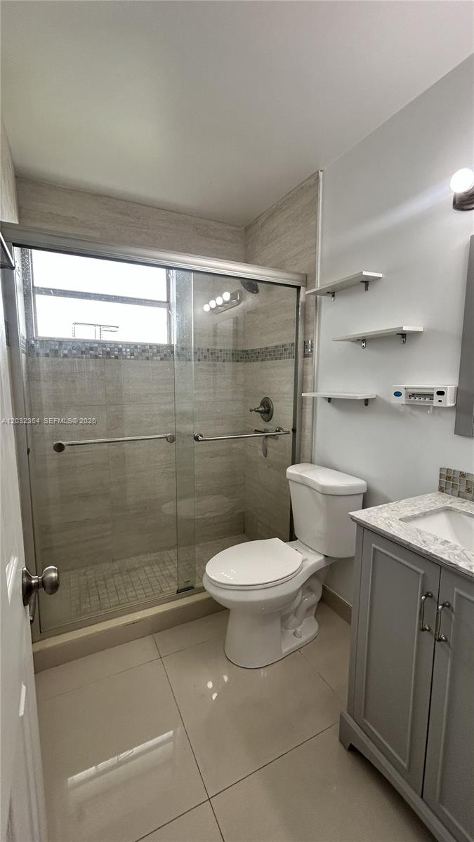 A bathroom features a glass-enclosed shower, a white toilet, and a grey vanity cabinet — 10377 N Kendall Dr # K8, Miami FL 33176, MIAMI, FL