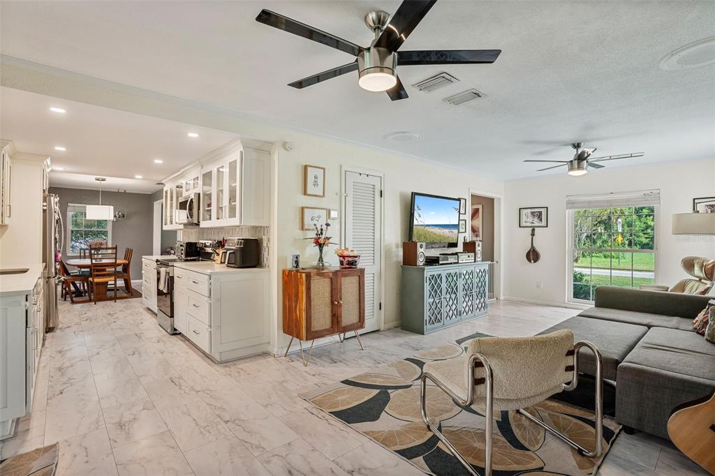 A white kitchen features marble-look tile floors, quartz countertops, and glass-front upper cabinets — 2464 LYDIA WAY, NEW SMYRNA BEACH, FL