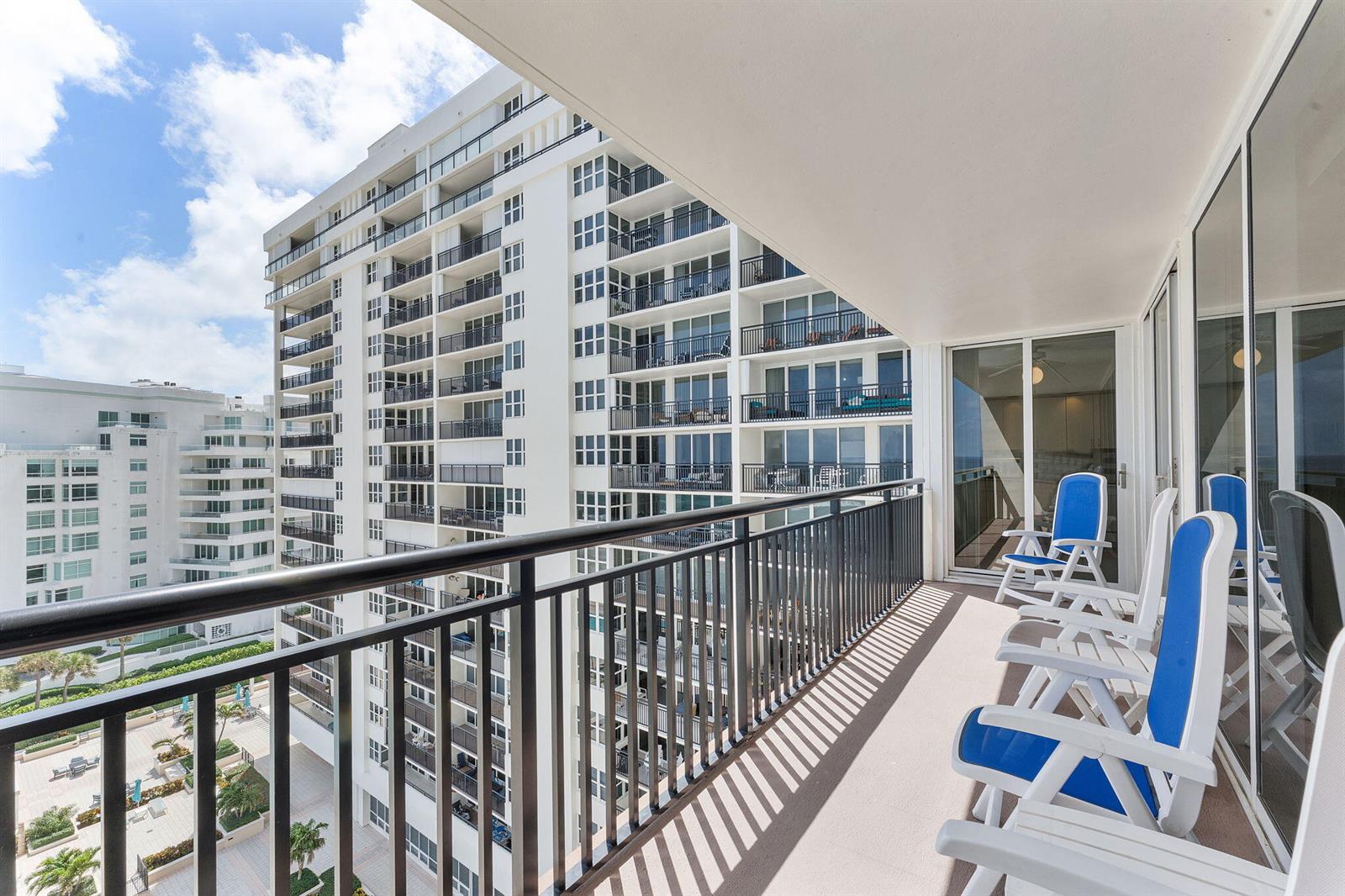 A balcony with blue and white chairs overlooks a tall apartment building and courtyard — 2000 S Ocean Boulevard # 10h, Boca Raton FL 33432, BOCA RATON, FL