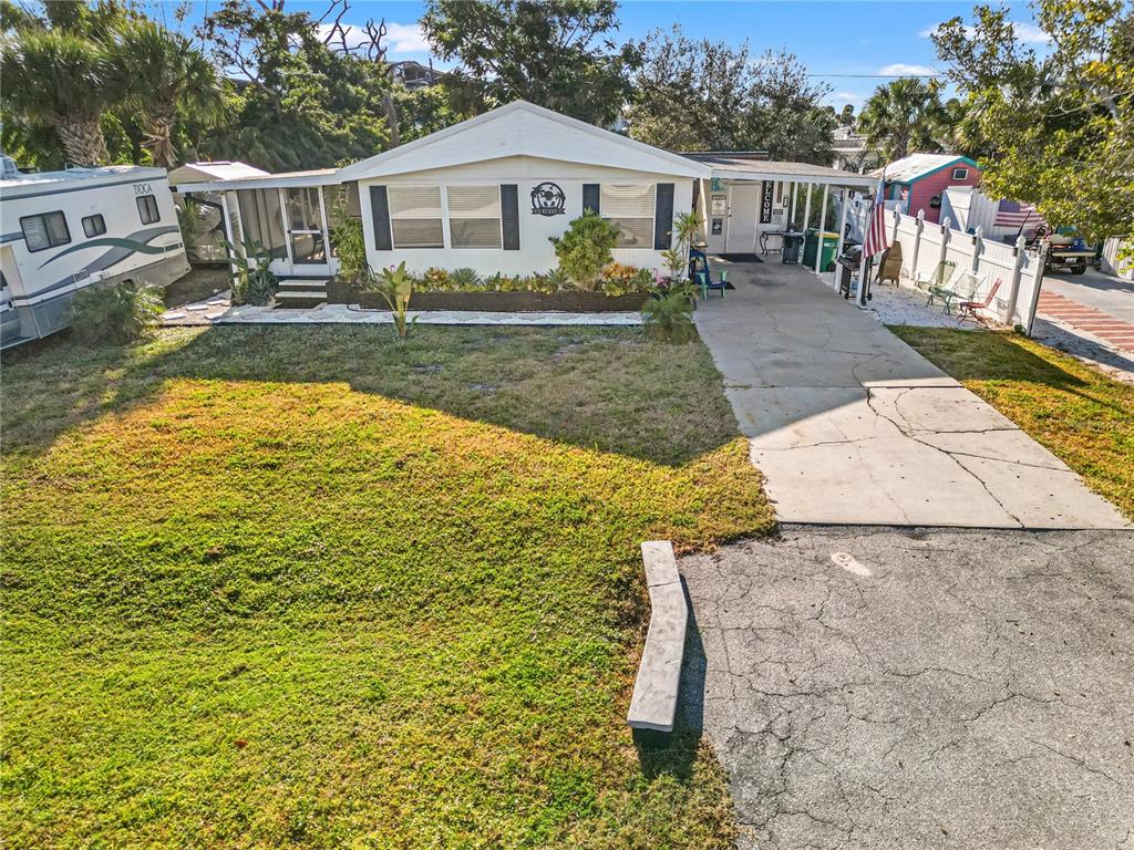 A single-story manufactured home with a concrete driveway, carport, and front yard — 3130 BOURBON STREET, ENGLEWOOD, FL