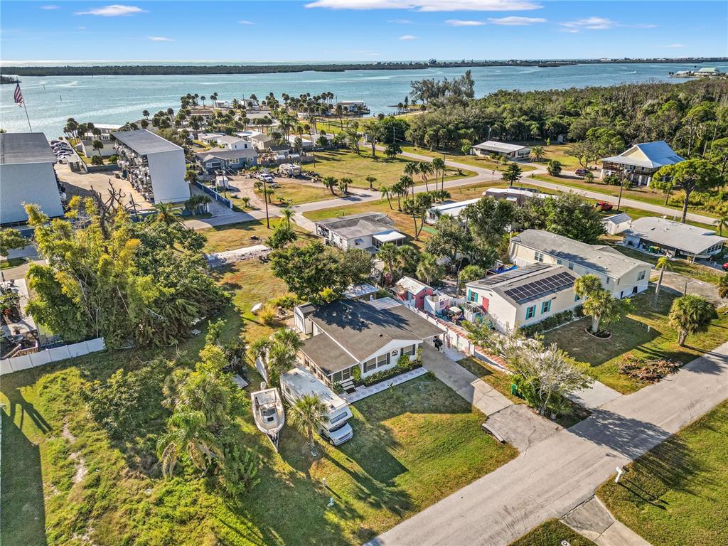 An aerial view shows a residential neighborhood with houses, a boat, and a nearby bay — 3130 BOURBON STREET, ENGLEWOOD, FL