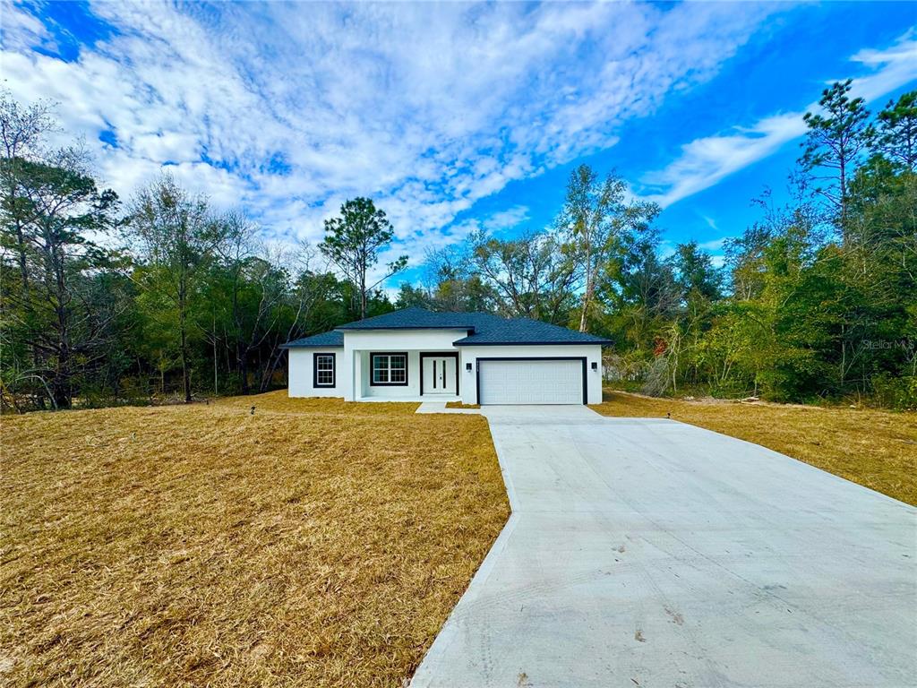 A single-story white house with a dark roof and a concrete driveway sits on a lot — 8428 N POCONO DRIVE, CITRUS SPRINGS, FL