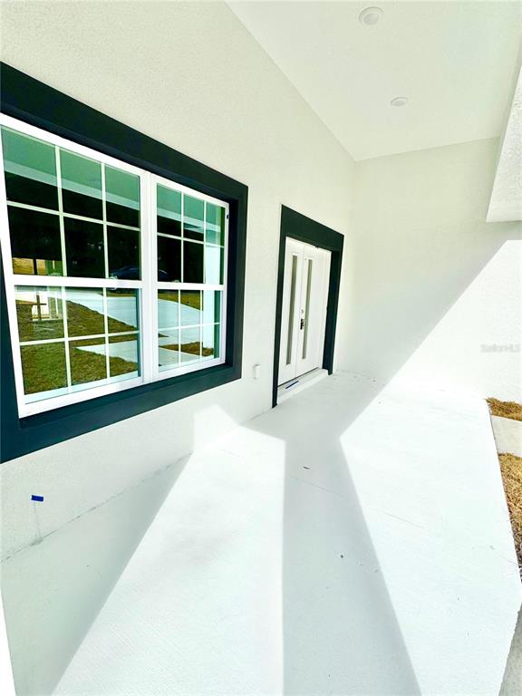 A white covered porch features a large window and a double door with dark frames — 8428 N POCONO DRIVE, CITRUS SPRINGS, FL