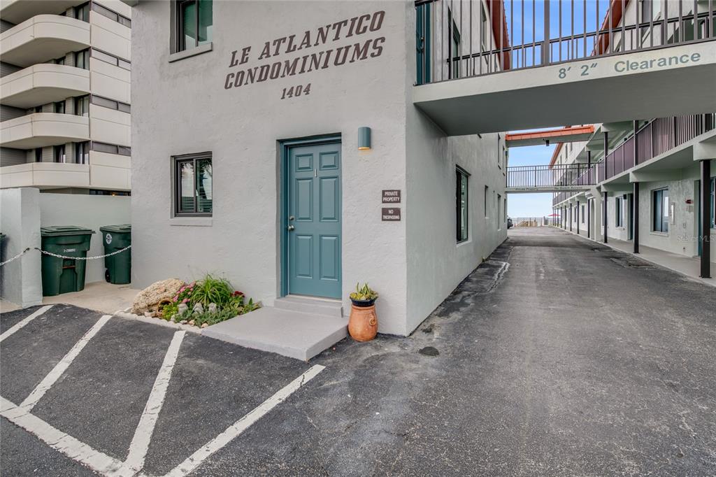 The exterior of a gray condominium building features a teal door and a parking area — 1404 N ATLANTIC AVENUE UNIT 10, DAYTONA BEACH, FL