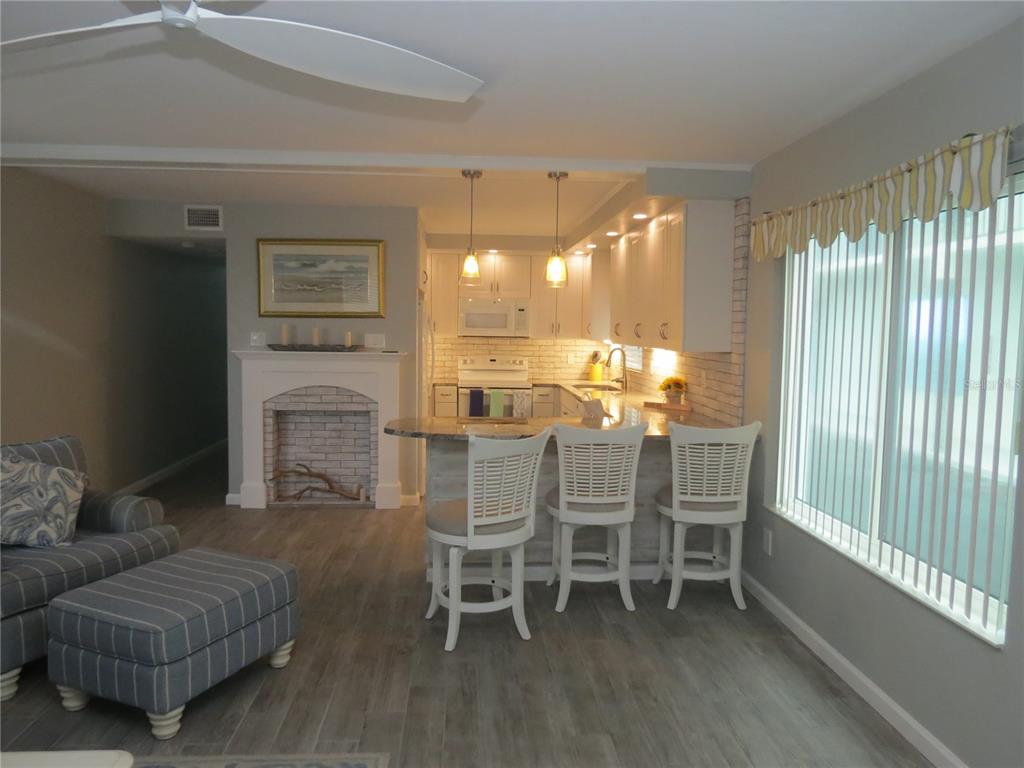 An open-concept kitchen with white cabinets and a breakfast bar overlooks a living area — 1404 N ATLANTIC AVENUE UNIT 10, DAYTONA BEACH, FL