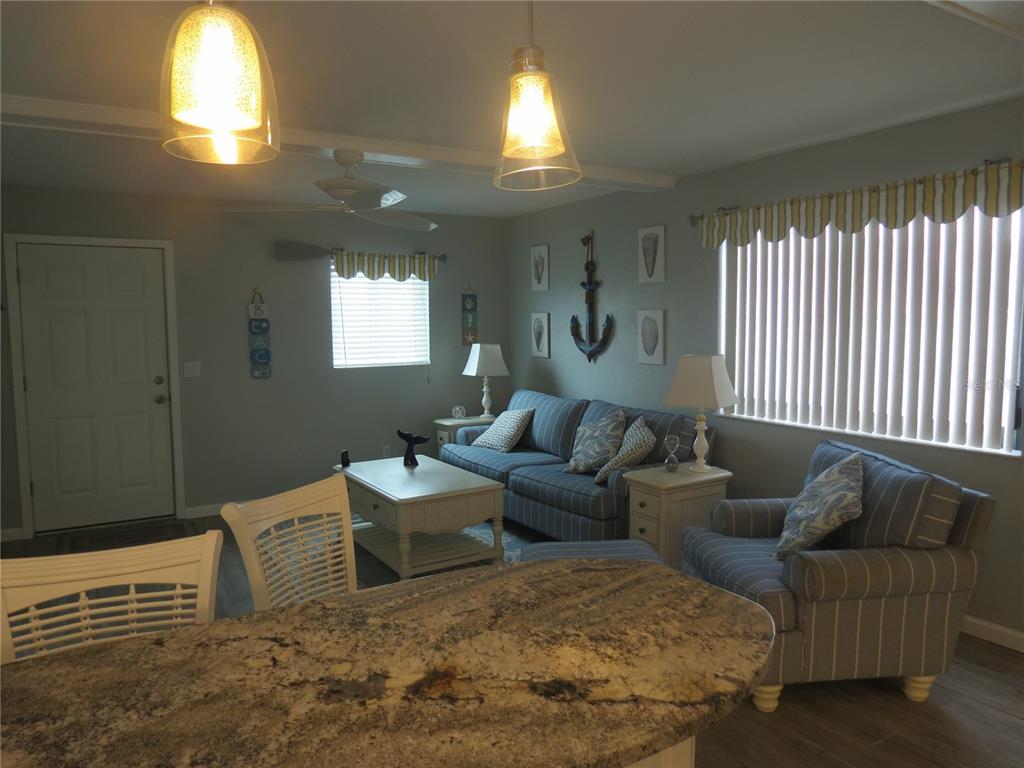 A living room features blue striped furniture, a granite-topped island, and nautical-themed wall decor — 1404 N ATLANTIC AVENUE UNIT 10, DAYTONA BEACH, FL