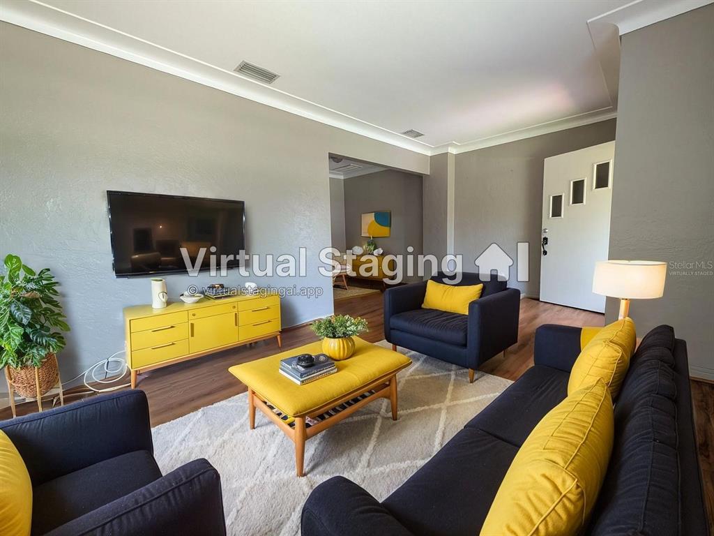 This living room features dark furniture, yellow accents, a television, and wood-look flooring — 206 12TH AVENUE N, ST PETERSBURG, FL