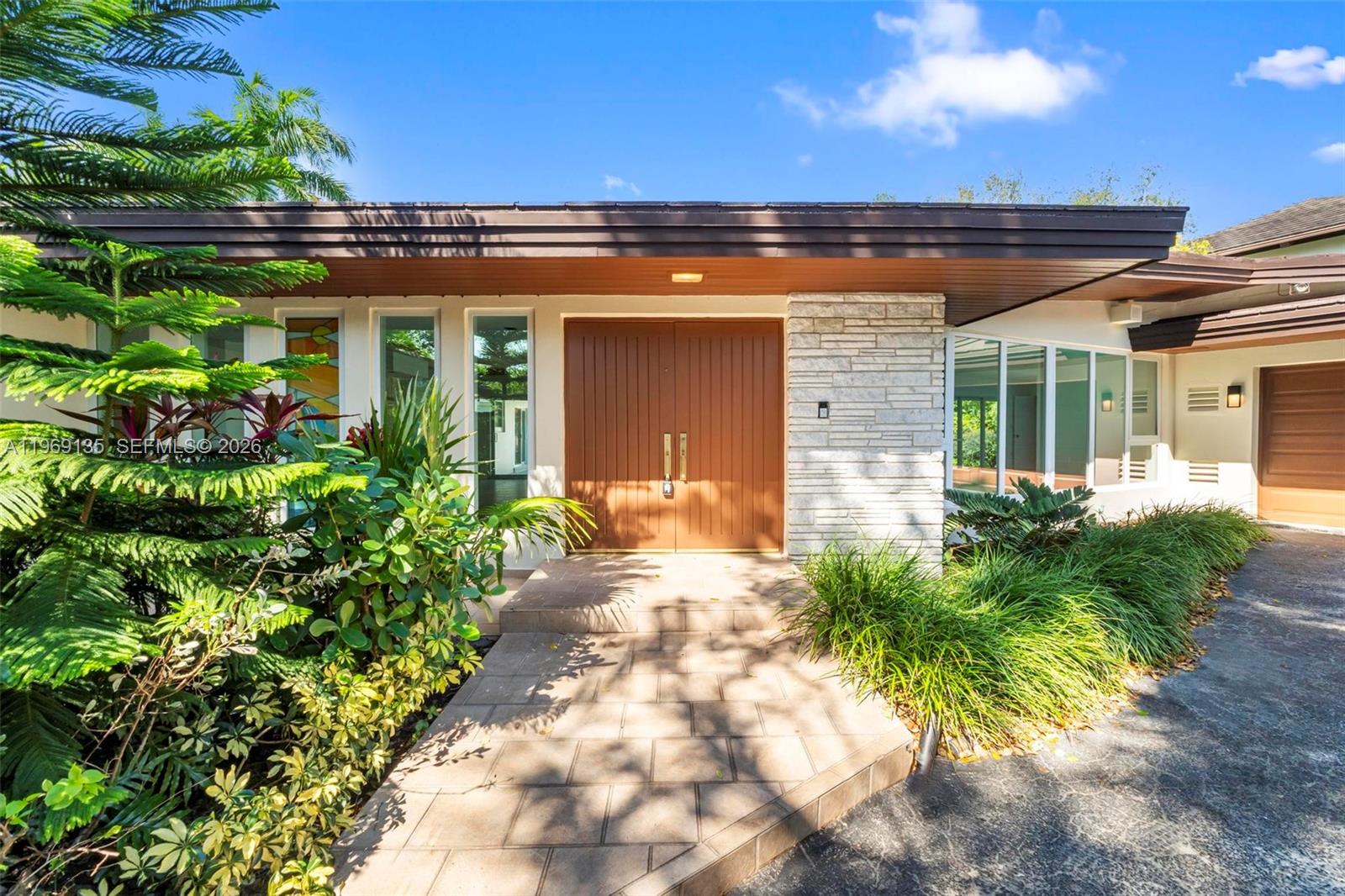 The exterior of a house features a double wood door, stone siding, and a walkway — 13060 Lerida St, Coral Gables FL 33156, CORAL GABLES, FL