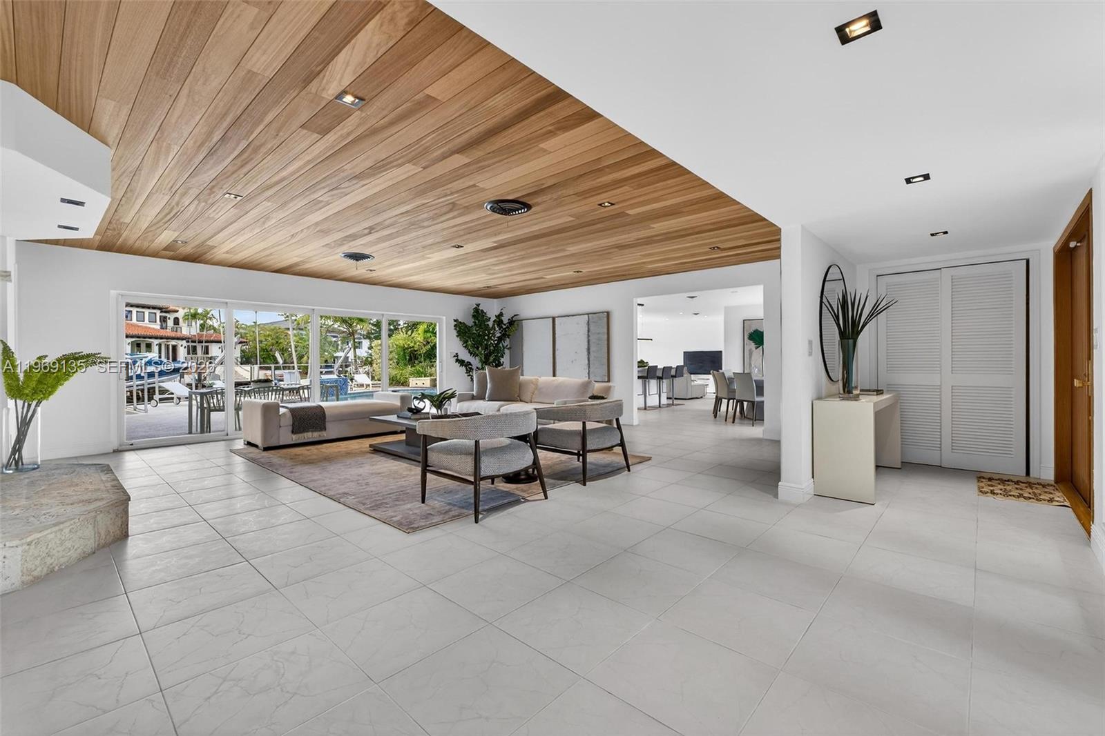 A living room features a wood-paneled ceiling, white tile floors, and sliding glass doors — 13060 Lerida St, Coral Gables FL 33156, CORAL GABLES, FL