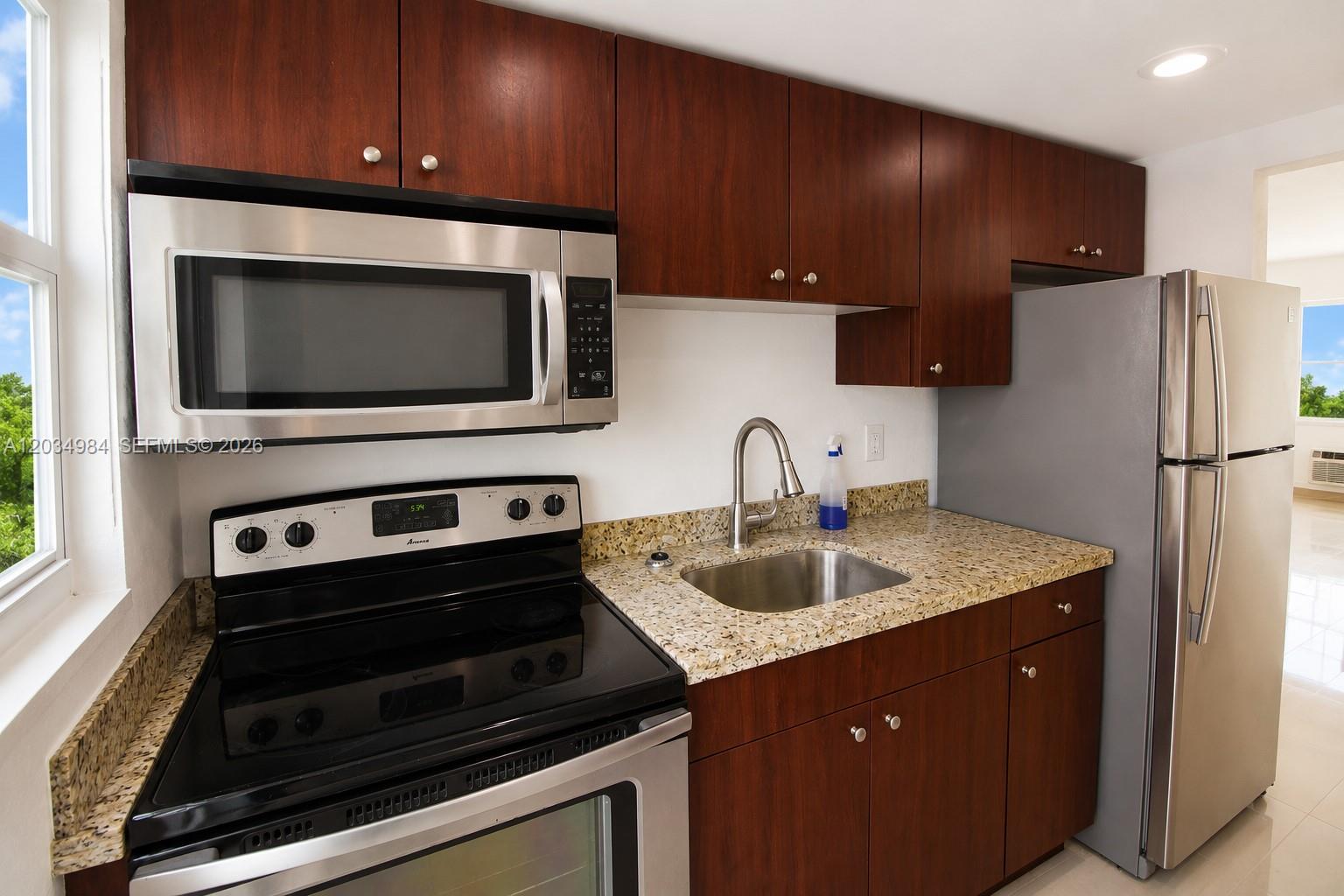 A kitchen features dark wood cabinets, stainless steel appliances, and speckled granite countertops — 3550 SW 9th Ter # 8B, Miami FL 33135, MIAMI, FL