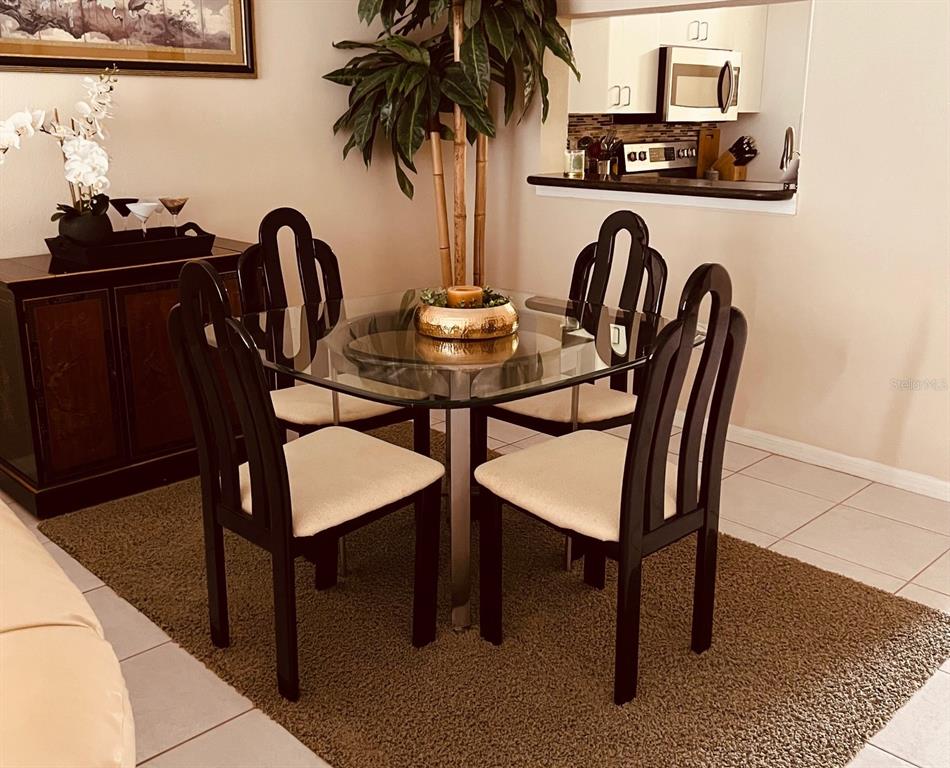 A dining area features a glass-topped table with four dark wood chairs on a rug — 9620 CLUB SOUTH CIRCLE UNIT 5101, SARASOTA, FL