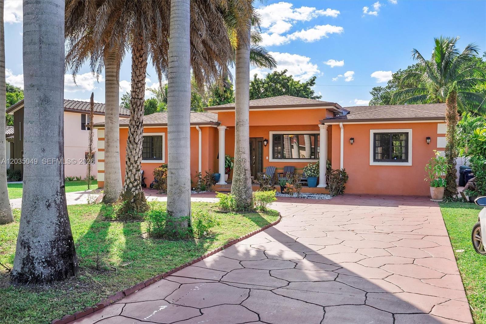 A single-story orange house with a paved driveway and palm trees in the front yard — 348 NE 118th St, Miami FL 33161, MIAMI, FL