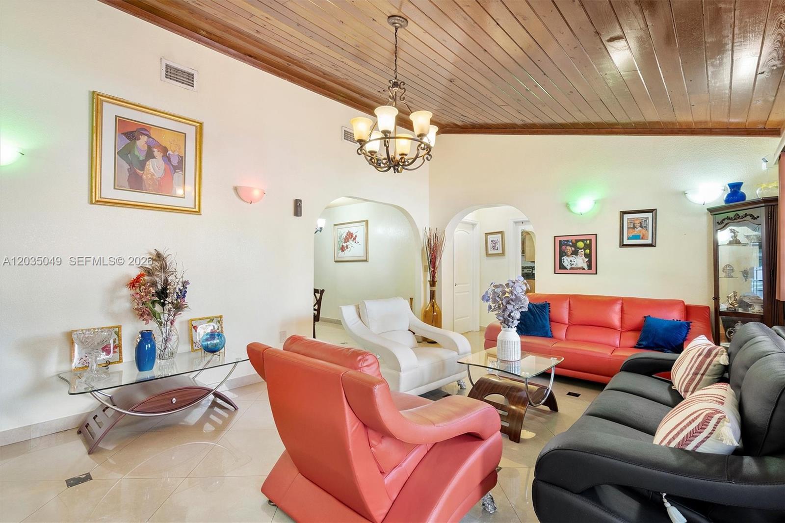 A living room features a wood-paneled vaulted ceiling, tile floors, and multiple seating areas — 348 NE 118th St, Miami FL 33161, MIAMI, FL