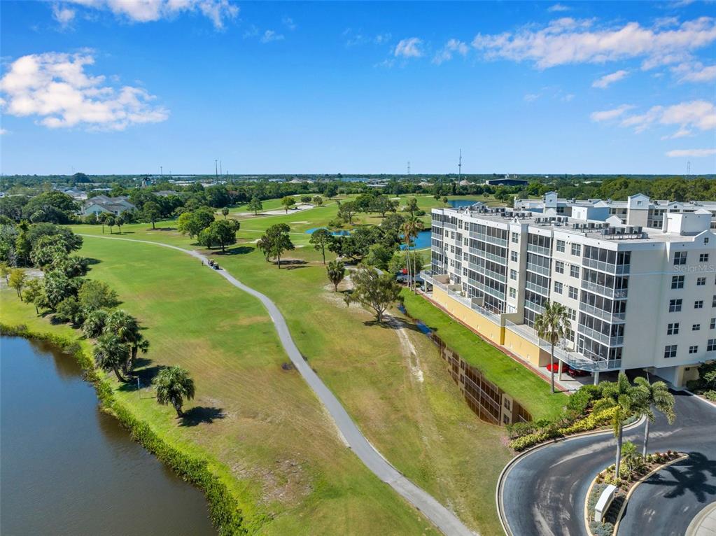 An aerial view shows a multi-story apartment building next to a golf course and pond — 1200 COUNTRY CLUB DRIVE UNIT 3105, LARGO, FL