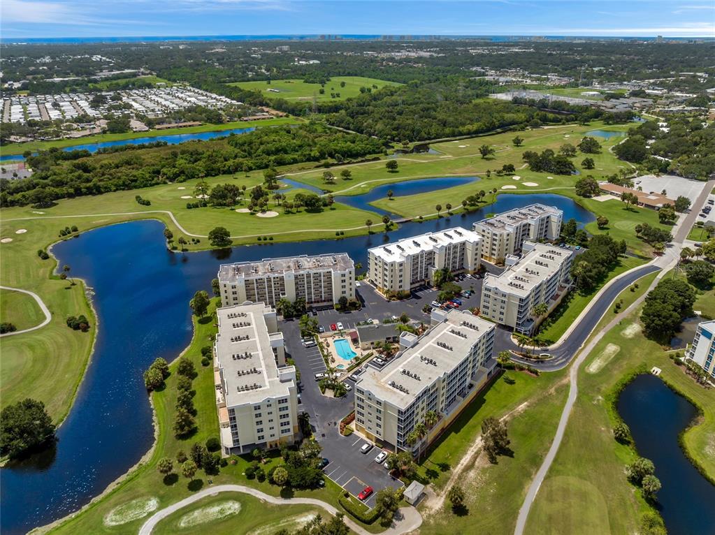 An aerial view shows several multi-story apartment buildings surrounded by a golf course and lakes — 1200 COUNTRY CLUB DRIVE UNIT 3105, LARGO, FL