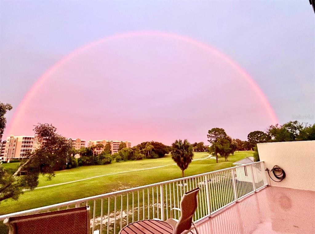 A balcony overlooks a grassy golf course under a large, pink-hued rainbow in the sky — 1200 COUNTRY CLUB DRIVE UNIT 3105, LARGO, FL