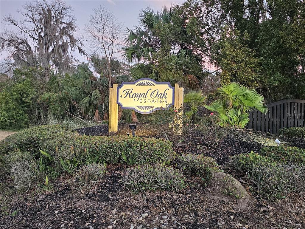 A sign for Royal Oak Estates stands in a landscaped garden with trees and shrubs — 2927 TANGERINE COURT, LEESBURG, FL