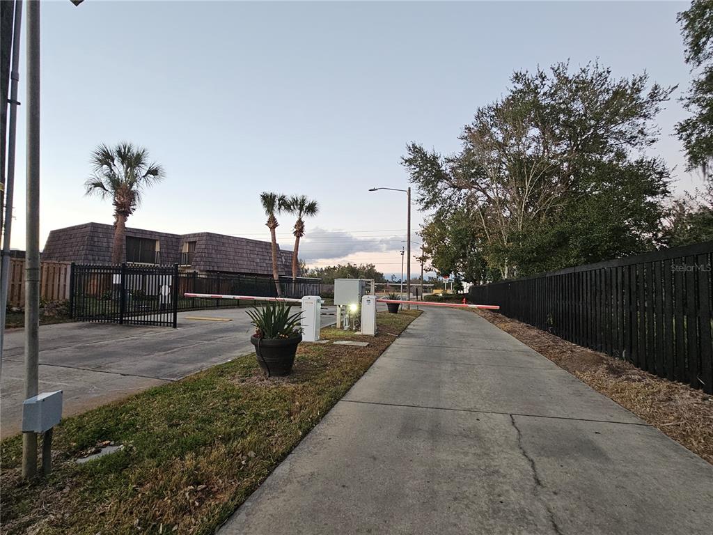 A gated entrance with a security arm, a black metal fence, and palm trees — 2927 TANGERINE COURT, LEESBURG, FL