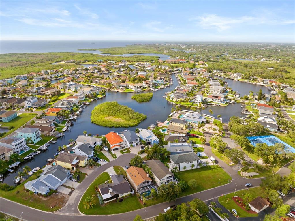 An aerial view of a waterfront residential neighborhood with canals, houses, and a tennis court — 4516 SEAGULL DRIVE UNIT 419, NEW PORT RICHEY, FL