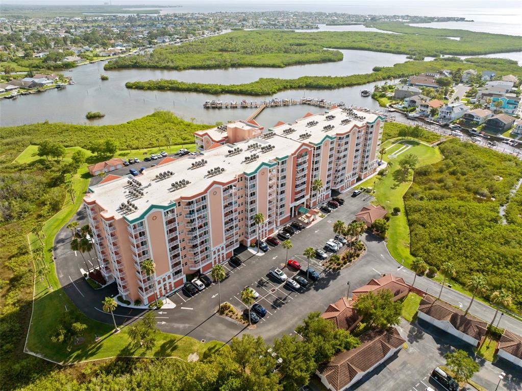 An aerial view shows a multi-story apartment building surrounded by mangroves and a waterfront — 4516 SEAGULL DRIVE UNIT 419, NEW PORT RICHEY, FL