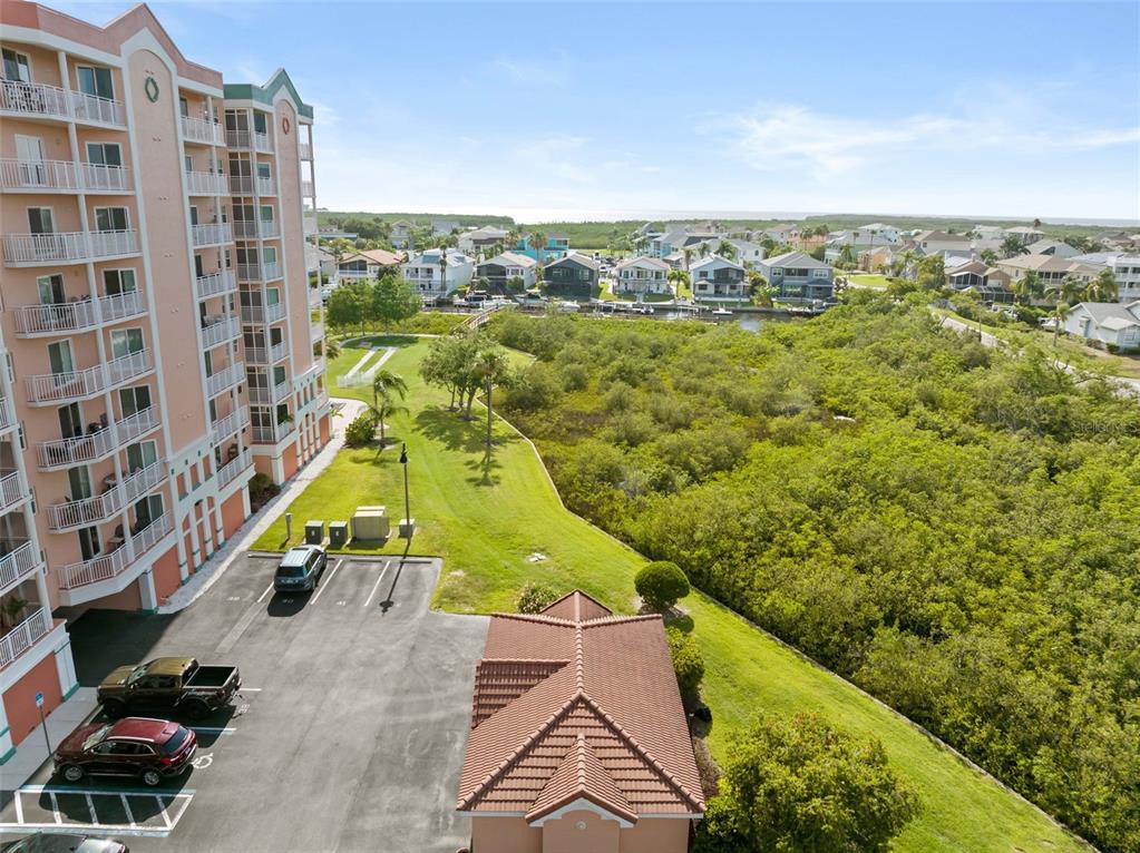 An aerial view shows a multi-story apartment building next to a parking lot and mangroves — 4516 SEAGULL DRIVE UNIT 419, NEW PORT RICHEY, FL