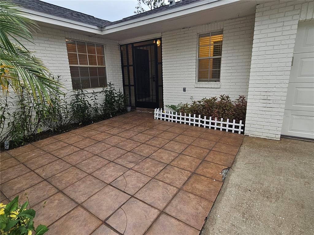 A tiled patio sits in front of a white brick house with a front door — 22360 SOUTHSHORE DRIVE, LAND O LAKES, FL