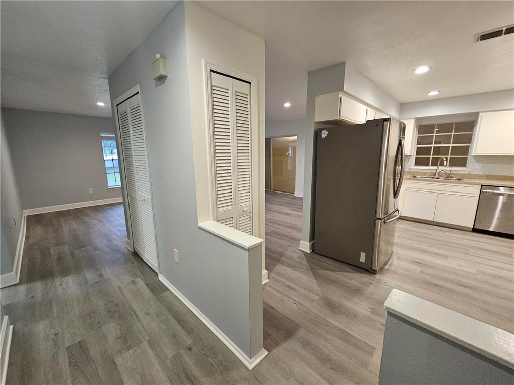 A kitchen with stainless steel appliances and light wood-look flooring opens to a living area — 22360 SOUTHSHORE DRIVE, LAND O LAKES, FL