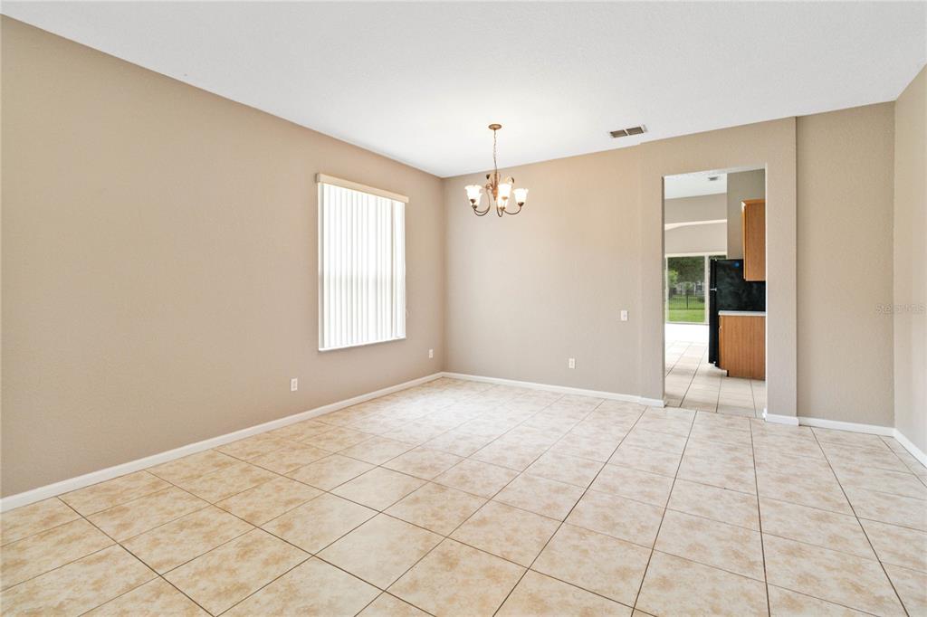 A dining room with beige walls, tile flooring, a chandelier, and a doorway to the kitchen — 2173 GRANGER AVENUE, KISSIMMEE, FL
