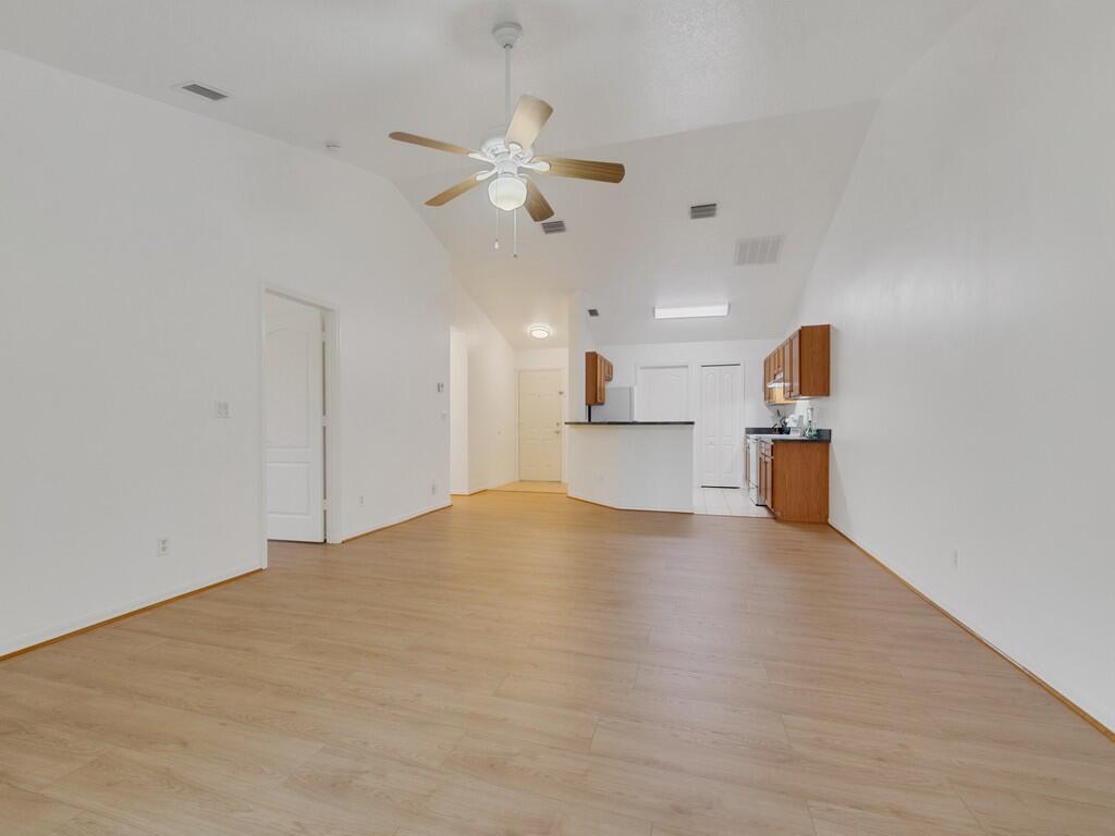 An open-concept living area with light wood-look flooring, white walls, and an adjoining kitchen — 11171 Airport Drive, Sebastian FL 32958, SEBASTIAN, FL