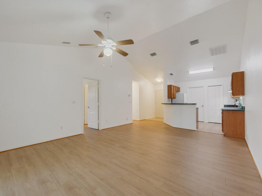 An open-concept living area features light wood-look flooring, vaulted ceilings, and a kitchen peninsula — 11171 Airport Drive, Sebastian FL 32958, SEBASTIAN, FL